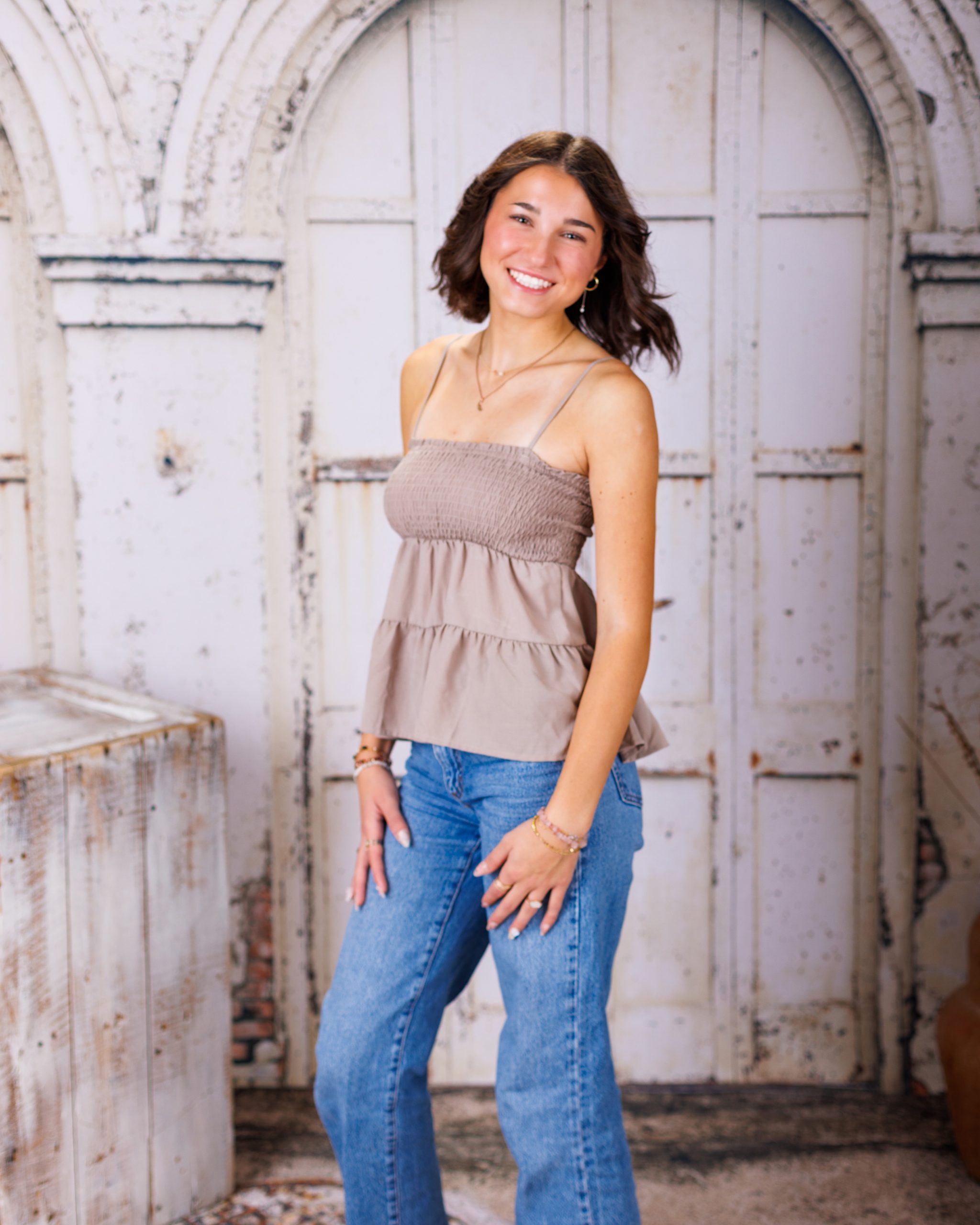 Anna posing in smocked peplum top with arched doorway backdrop at Woodhaven Senior Session