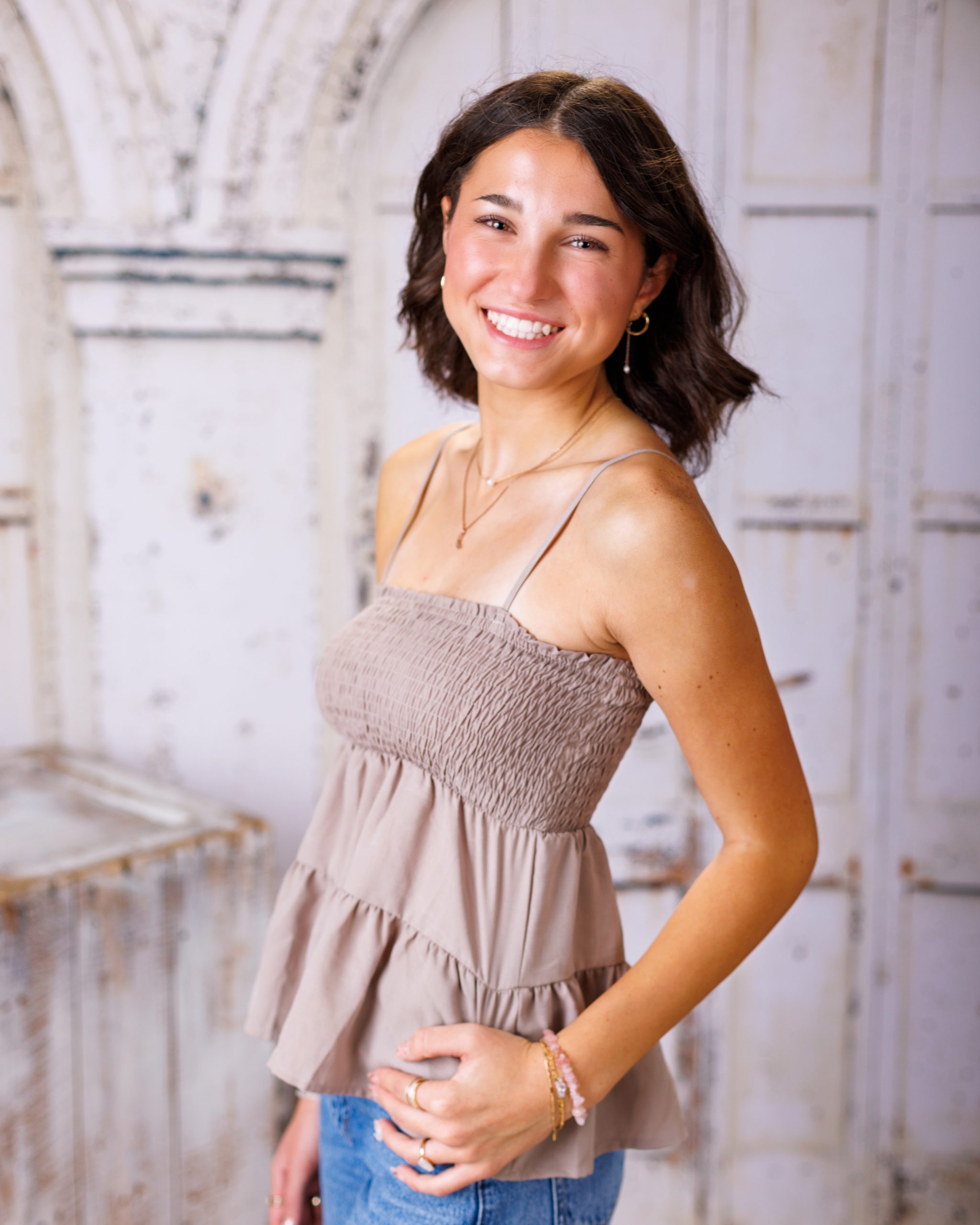 Anna posing in smocked peplum top with arched doorway backdrop at Woodhaven Senior Session