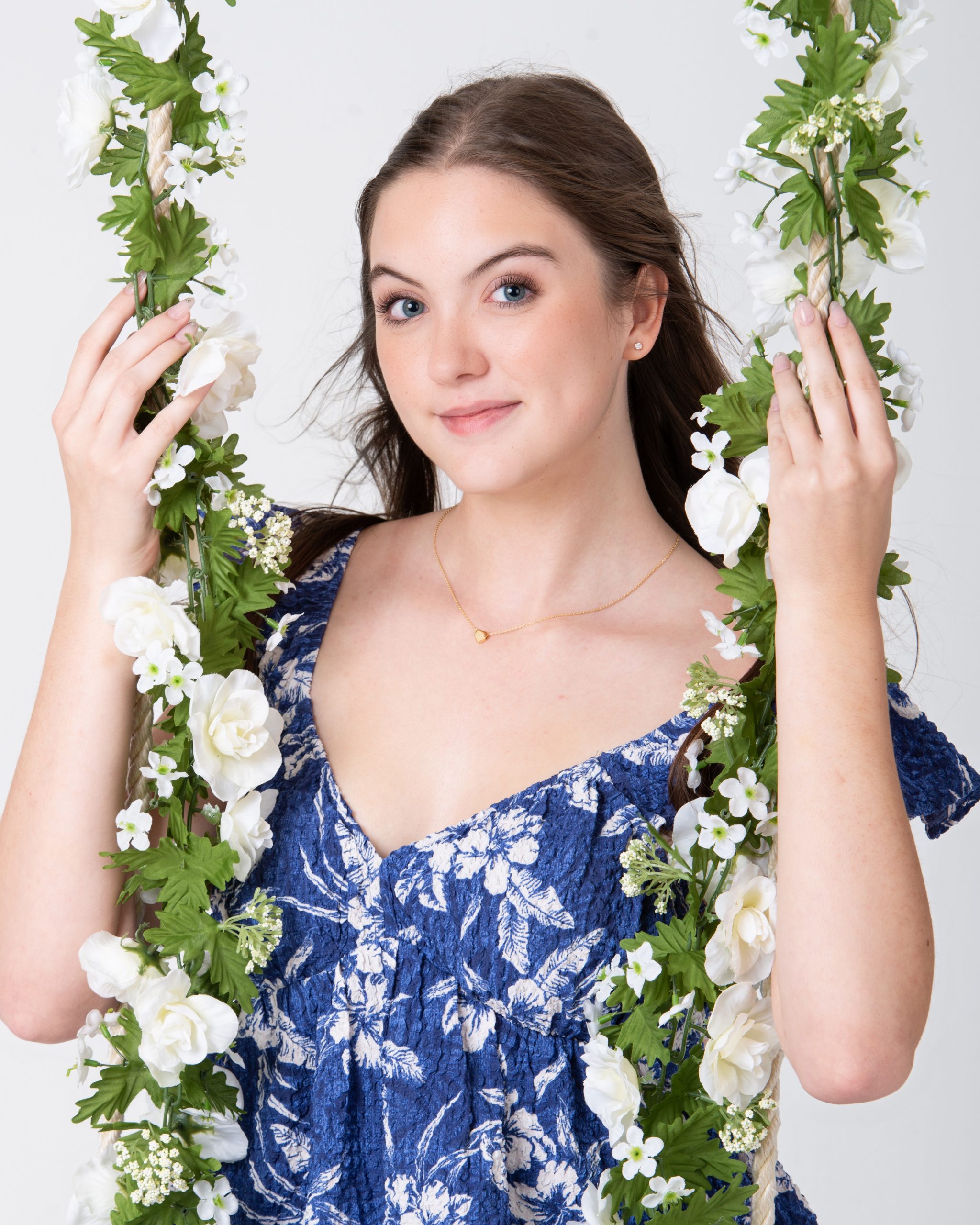 Senior woman holding floral swing in blue floral dress during Downriver photo session