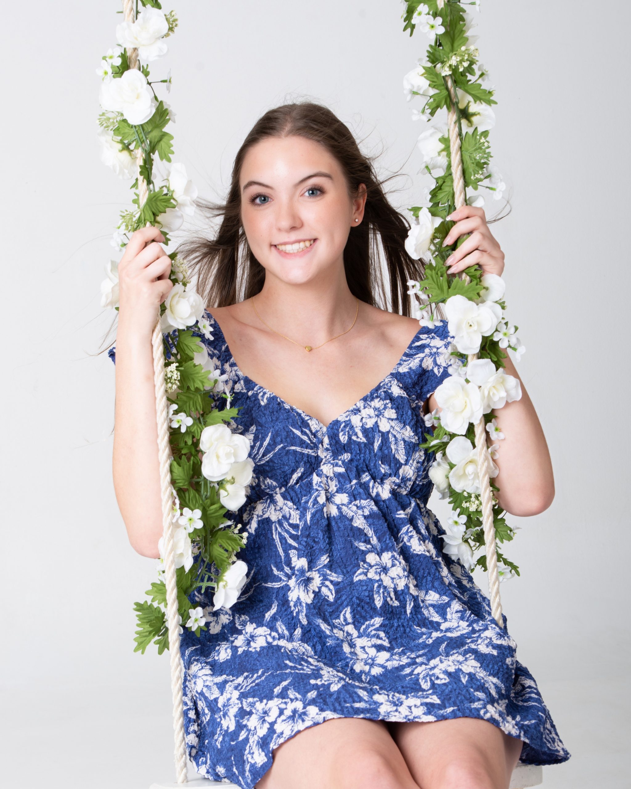 Senior woman holding floral swing in blue floral dress during Downriver photo session
