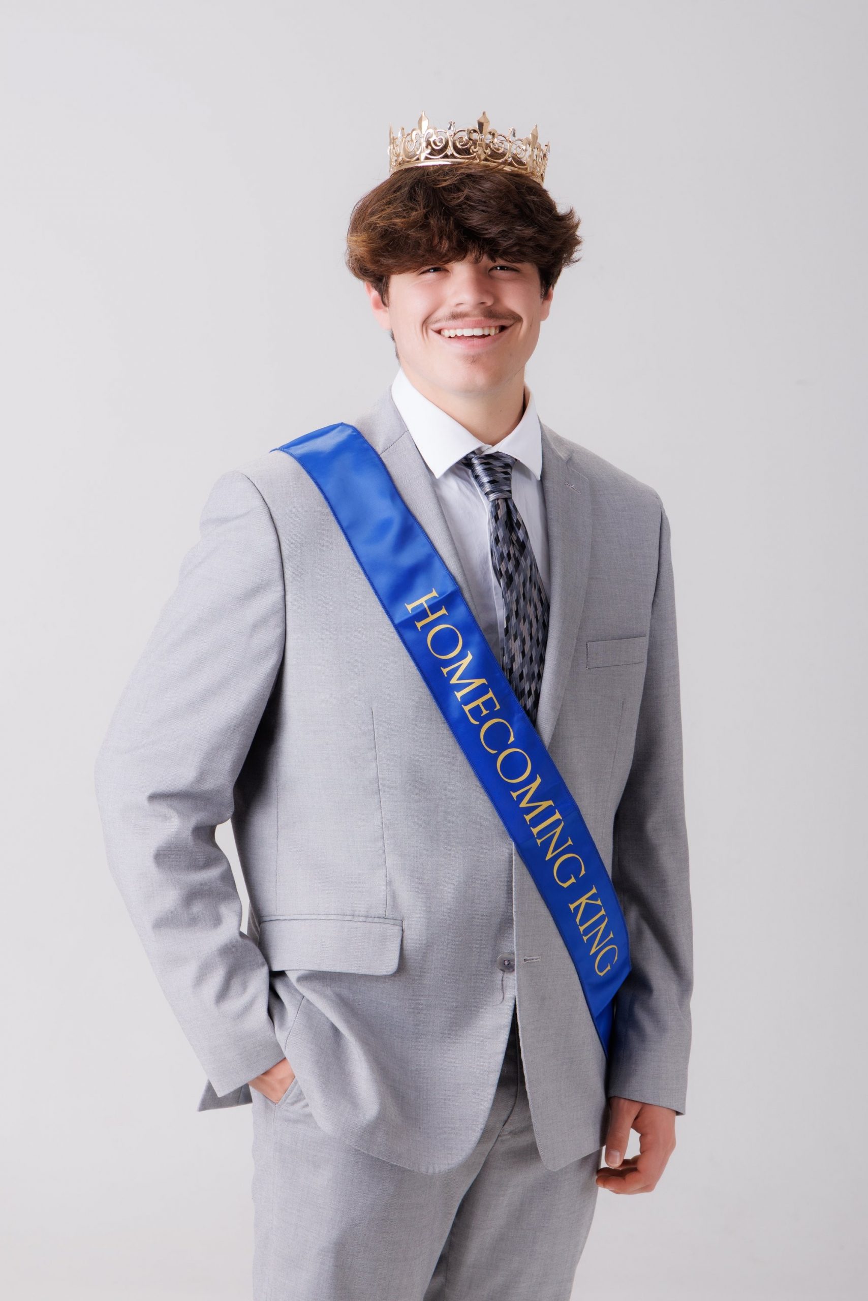 Luke in blue graduation gown and cap with 'Class of 2026' chalkboard, Downriver photo studio