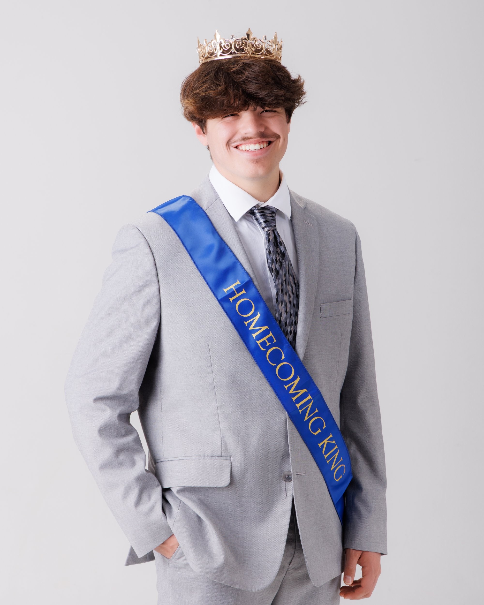 Luke in blue graduation gown and cap with 'Class of 2026' chalkboard, Downriver photo studio