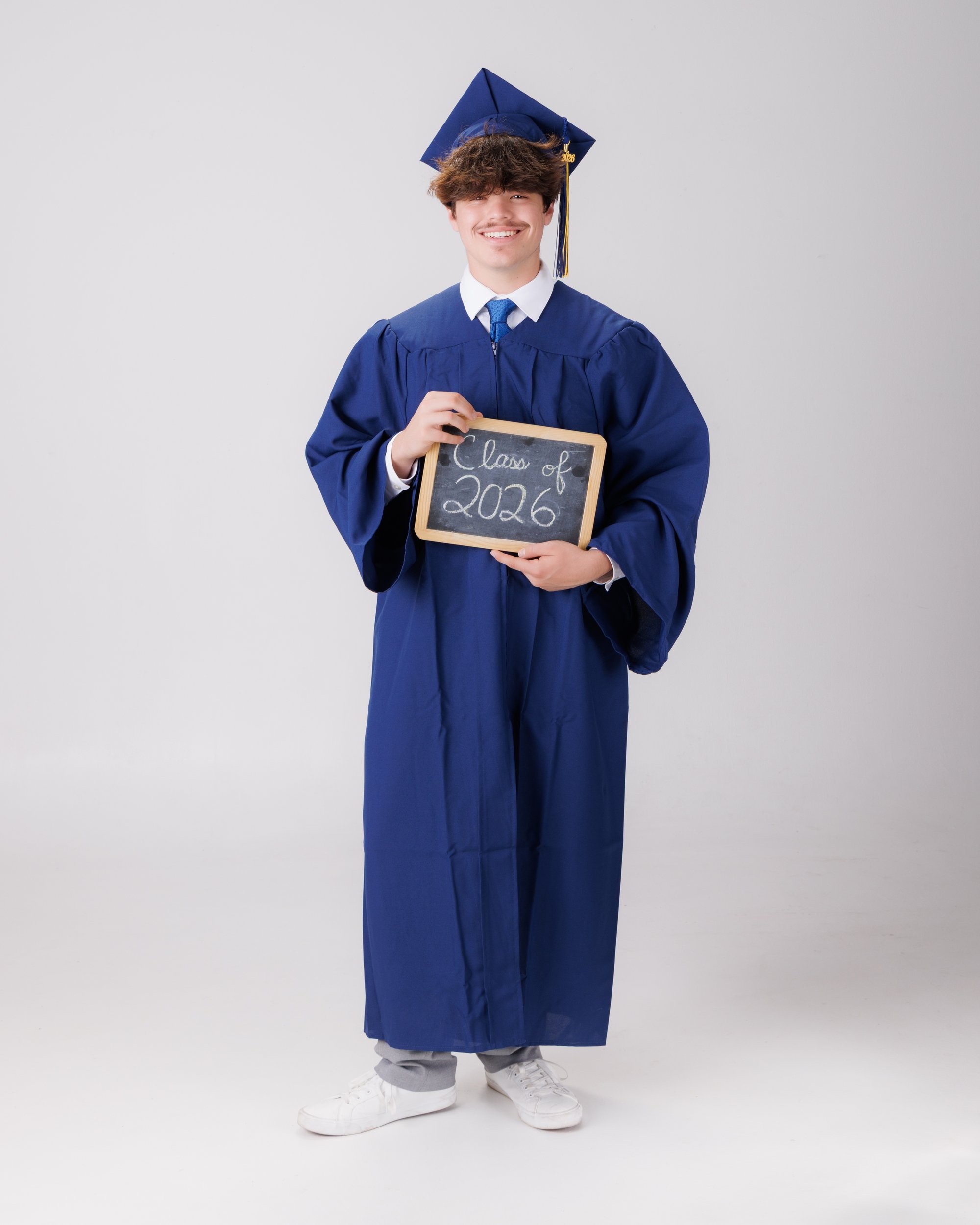 Luke in blue graduation gown and cap with 'Class of 2026' chalkboard, Downriver photo studio