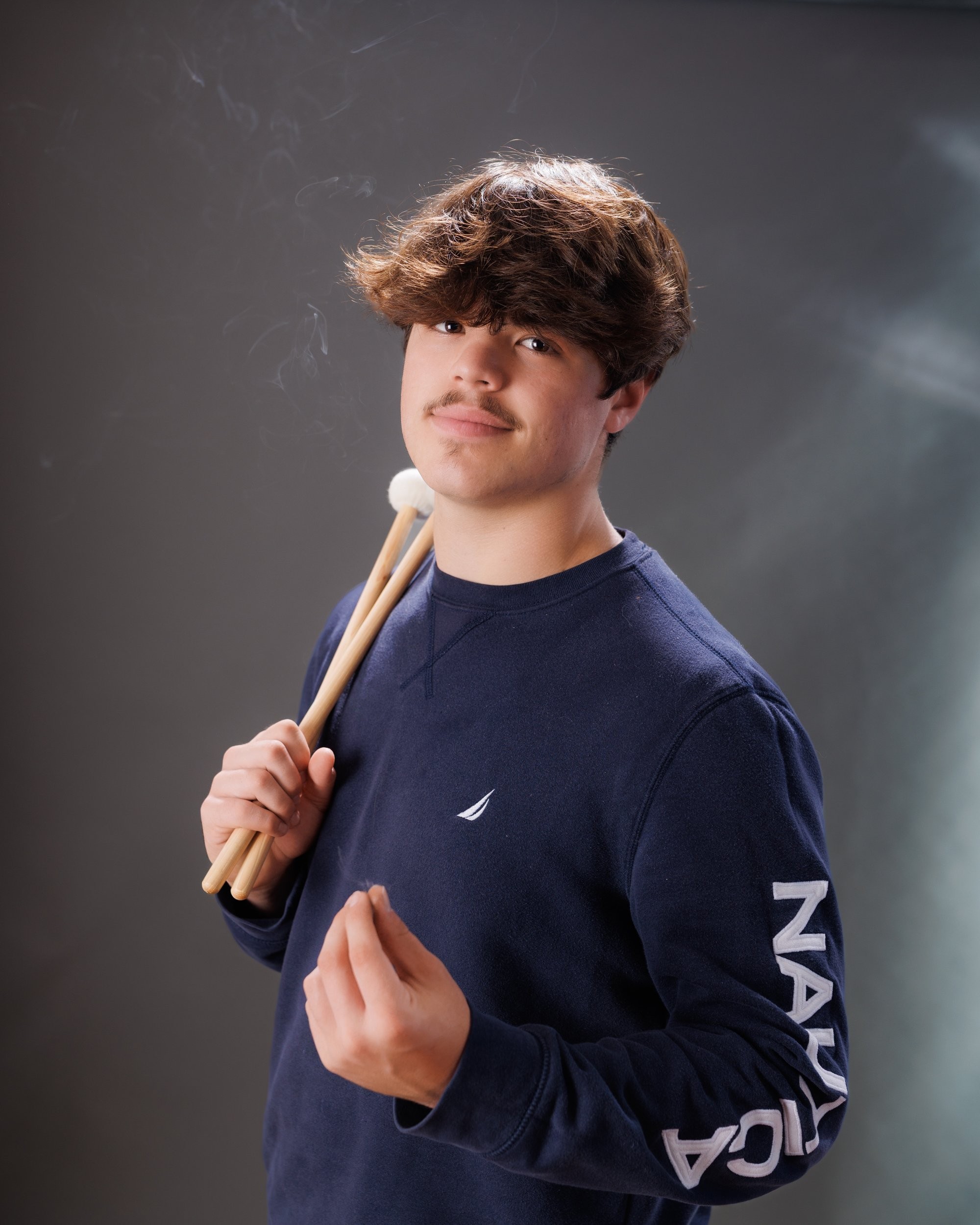 Luke in blue graduation gown and cap with 'Class of 2026' chalkboard, Downriver photo studio