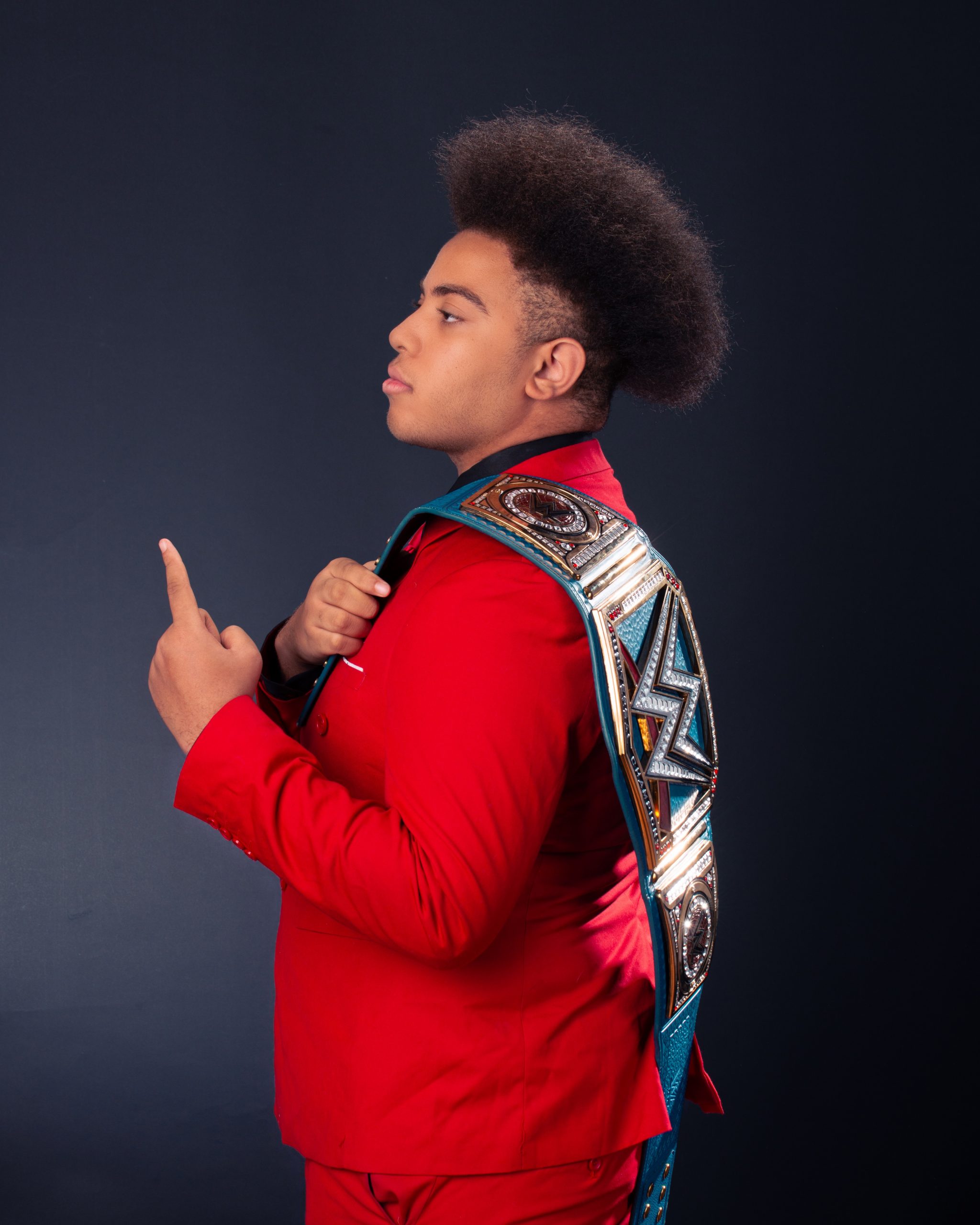 Black and white senior portrait of model wearing lei and holding WWE belt