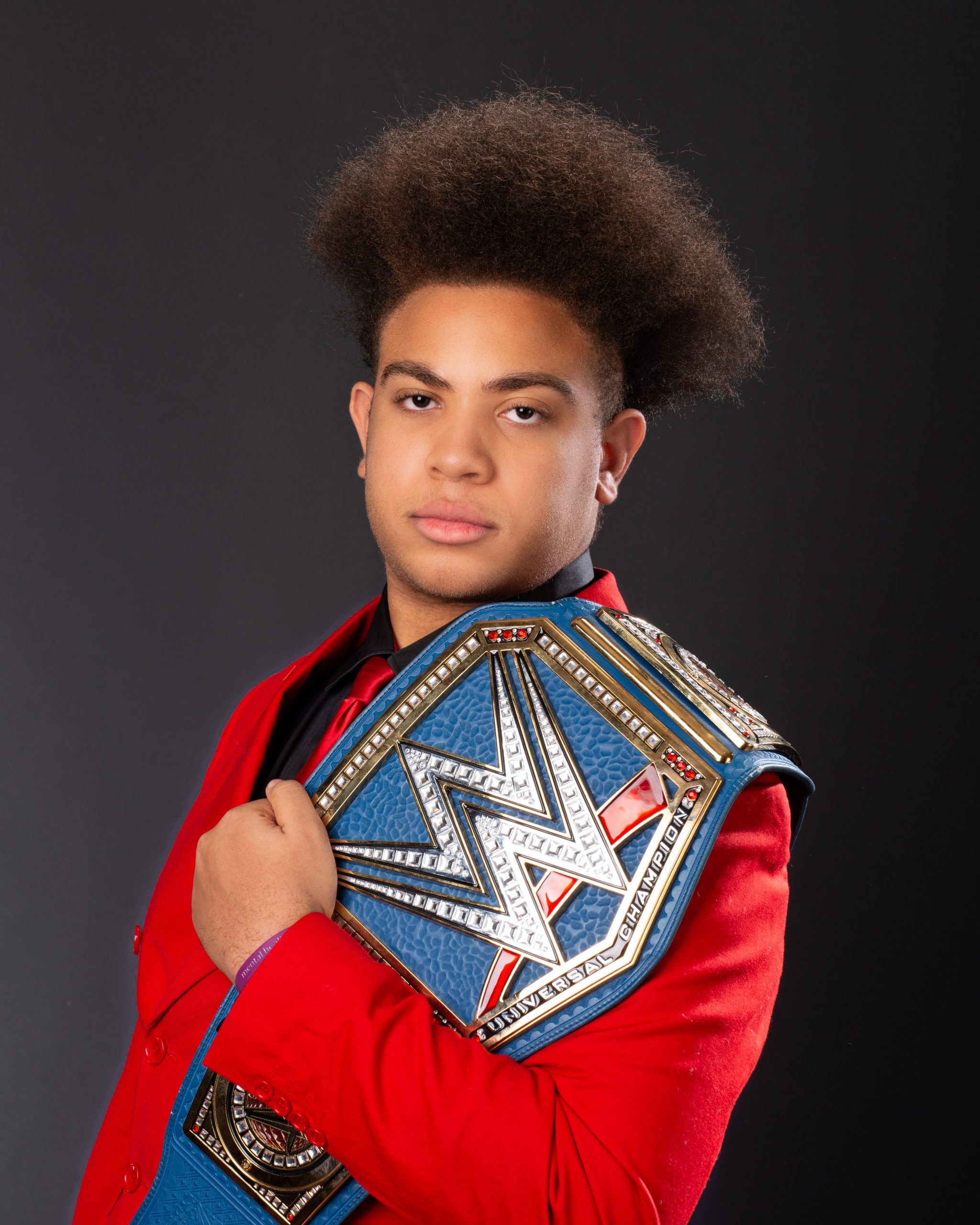 Black and white senior portrait of model wearing lei and holding WWE belt