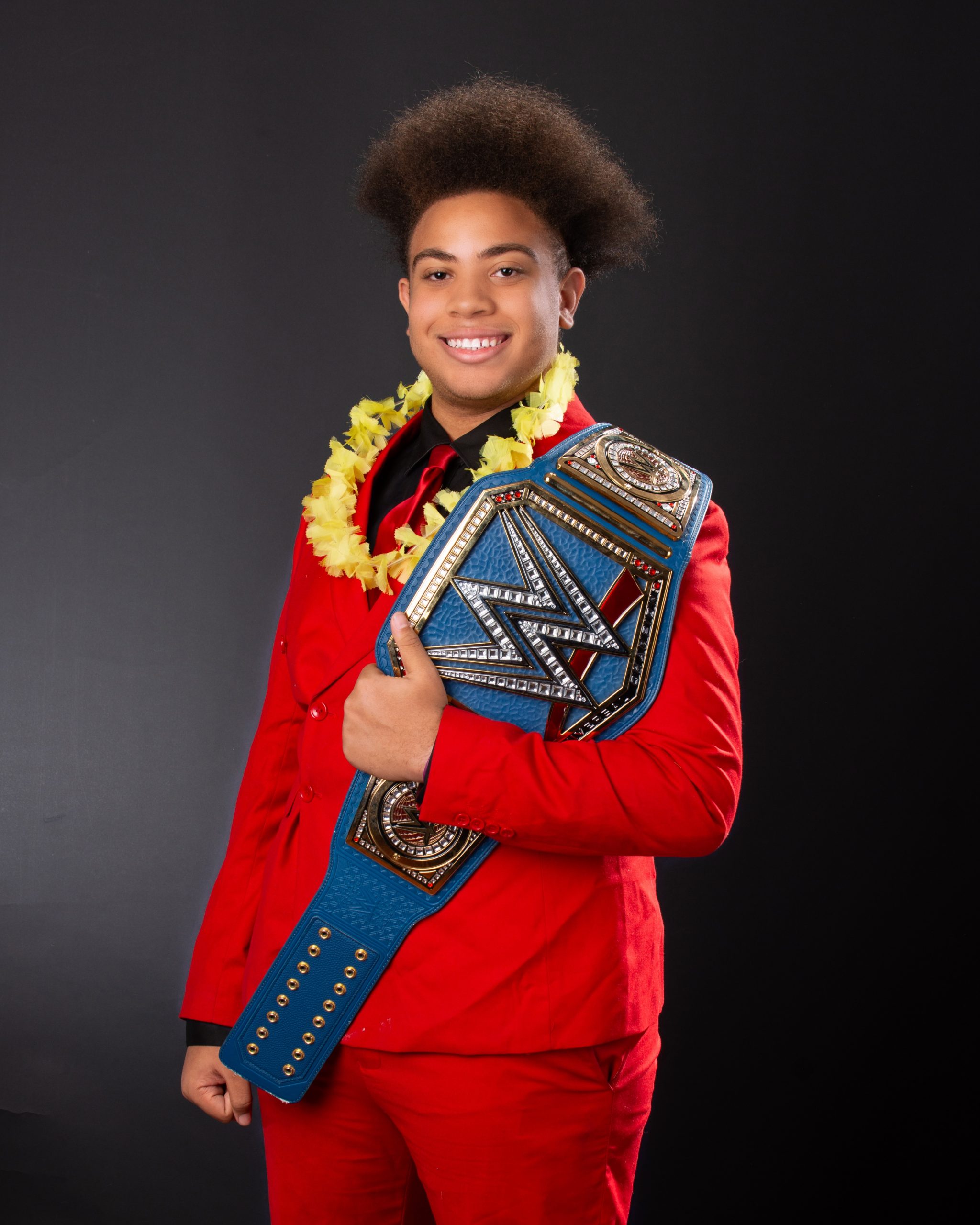 Black and white senior portrait of model wearing lei and holding WWE belt