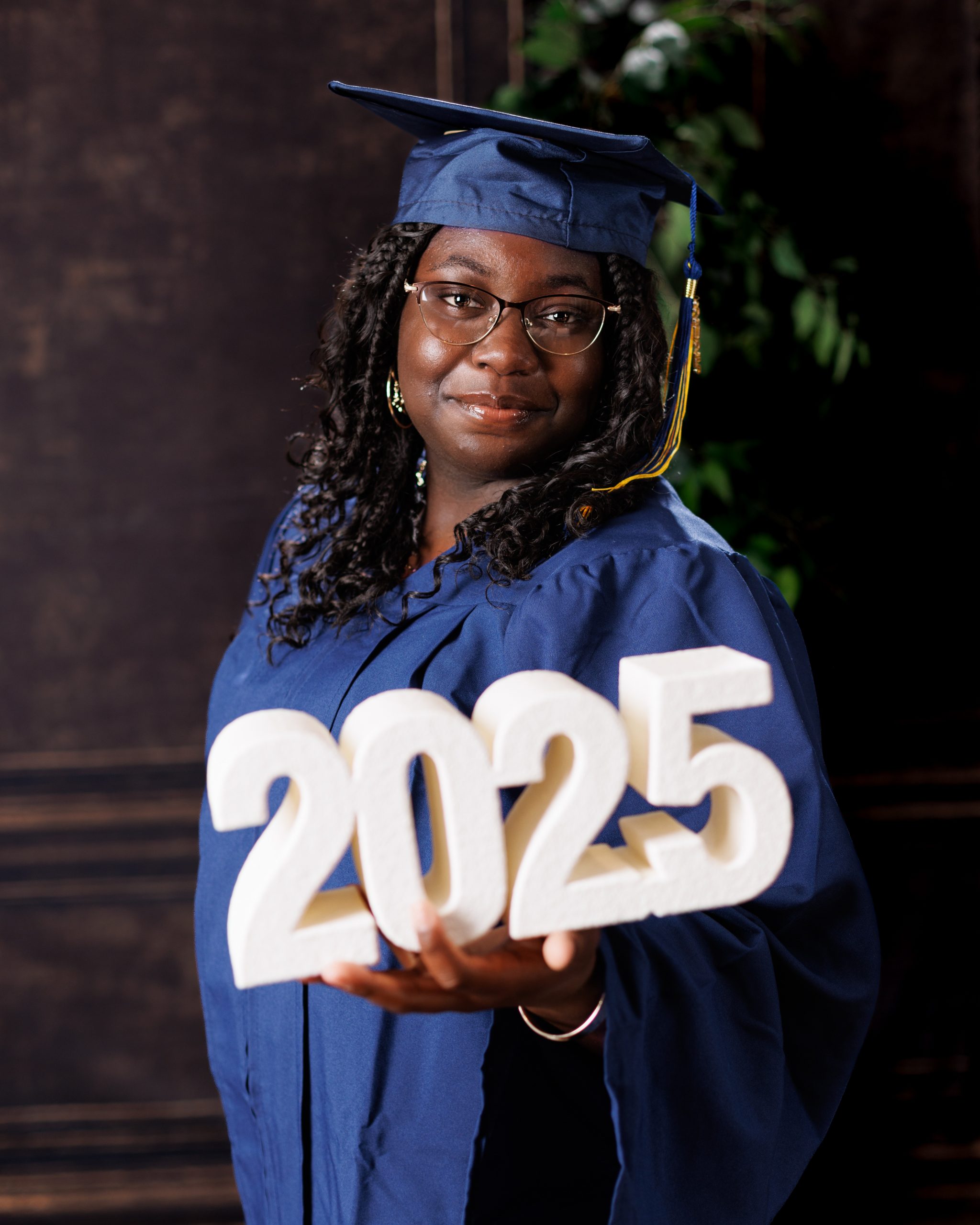 Wyandotte graduation photo of a woman holding '2025' numbers in blue gown